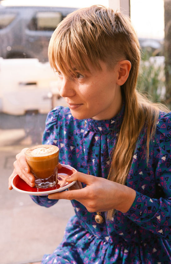 Hip young girl with undercut and vintage dress drinking latte in Oakland Pittsburgh Location of Redhawk Coffee Roasters